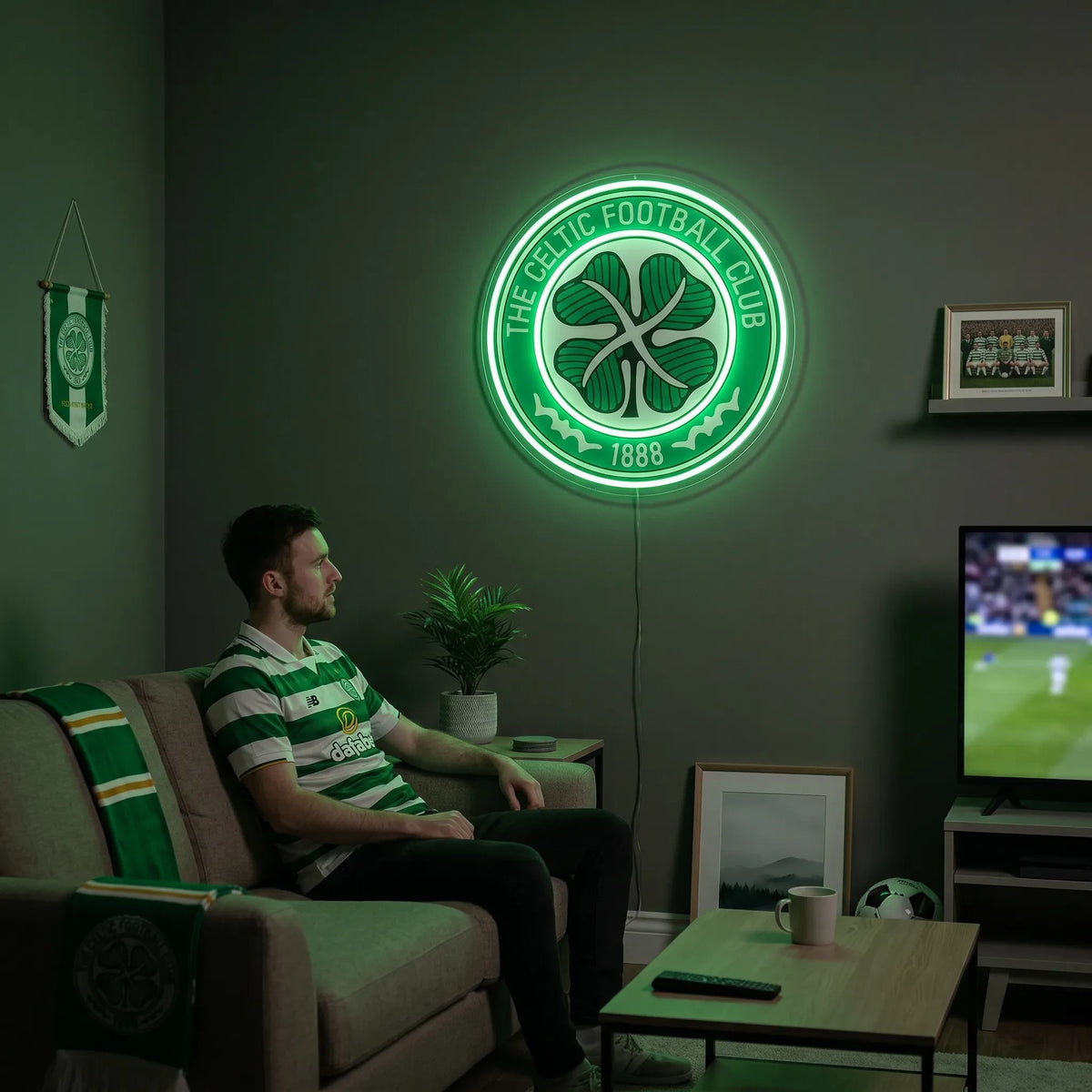 A man holding a circular The Celtic Football Club crest LED neon sign featuring the traditional four-leaf clover logo glowing in a vibrant green light