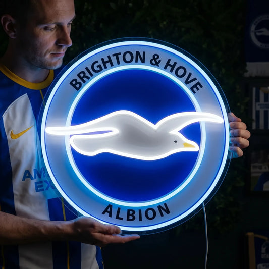 A man holding a custom Bradford City AFC football club crest LED neon sign featuring the BC initials, a bantam rooster on top, and The Bantams ribbon glowing in warm yellow and white light