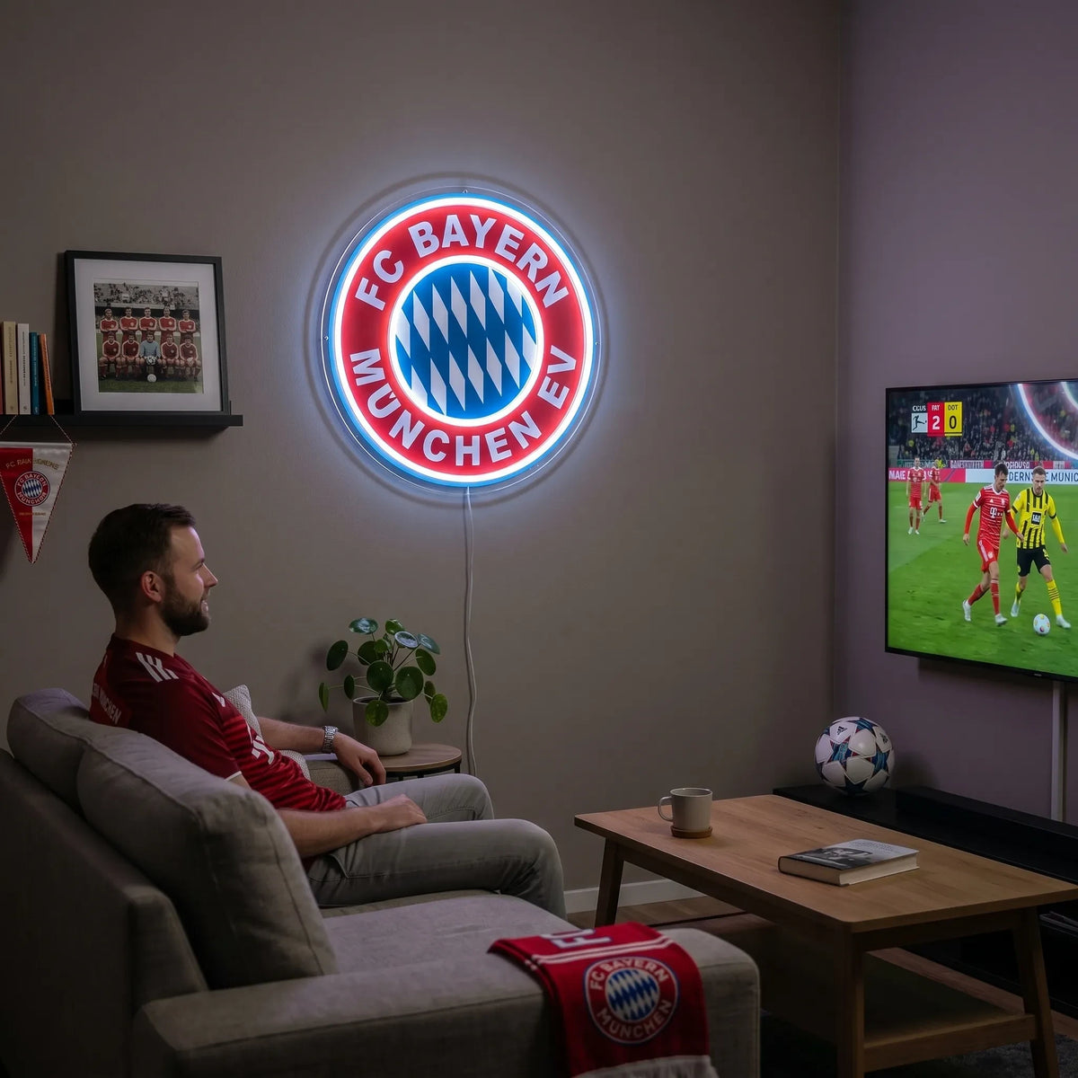 A man holding a large circular FC Bayern München football club crest LED neon sign glowing in bright blue and red light