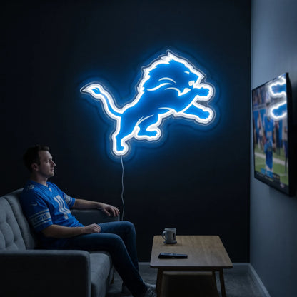 A smiling man holding a large custom-shaped Detroit Lions NFL football team logo LED neon sign featuring the iconic leaping lion silhouette glowing in a vibrant Honolulu blue and bright white light