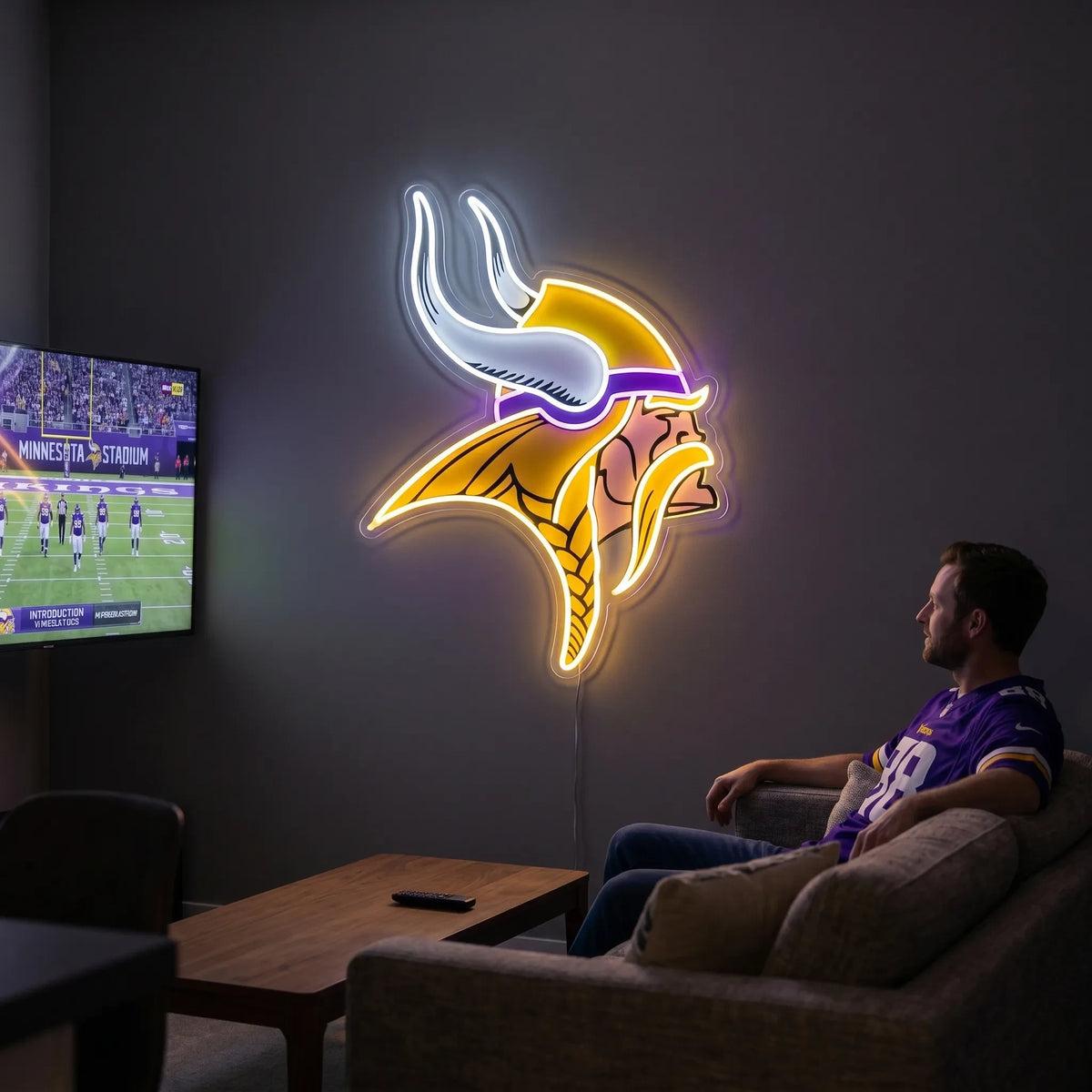 A smiling man holding a large custom-shaped Minnesota Vikings NFL football team logo LED neon sign featuring the Norseman head profile with a purple headband, a braided blonde mustache and hair, and white horns glowing in vibrant purple, gold yellow, and bright white light