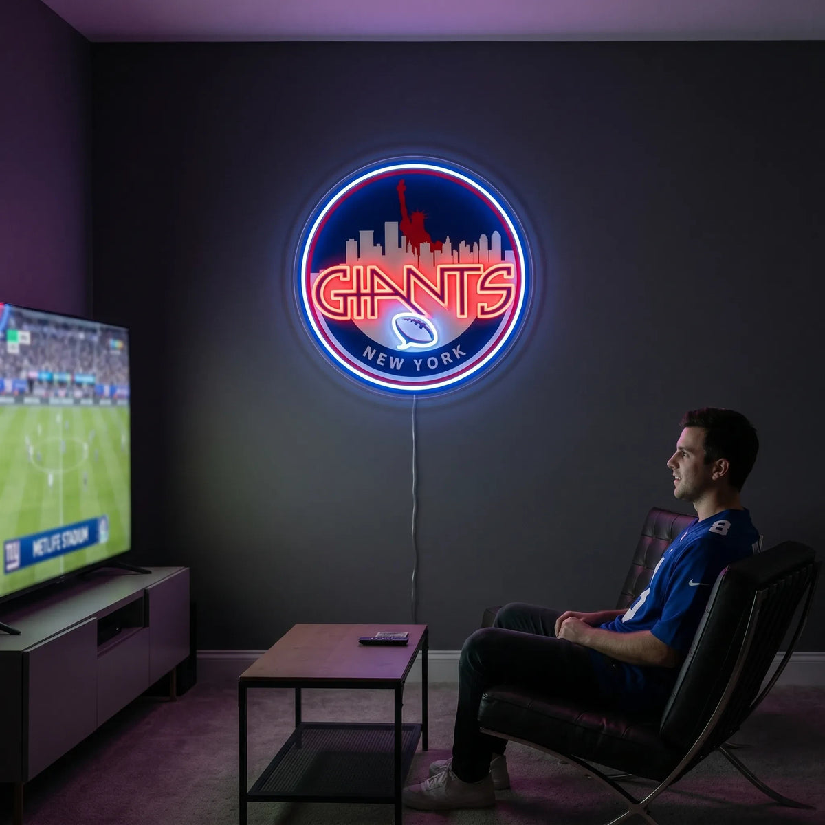 A smiling man holding a large circular New York Giants NFL football team themed LED neon sign featuring a red Statue of Liberty and city skyline silhouette above the stylized red Giants wordmark and a glowing blue football symbol
