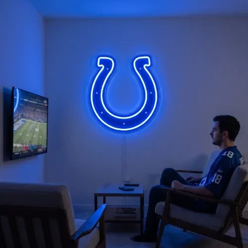 A man holding a large custom-shaped Indianapolis Colts NFL football team logo LED neon sign featuring the iconic blue horseshoe with seven white dots glowing in a vibrant blue light