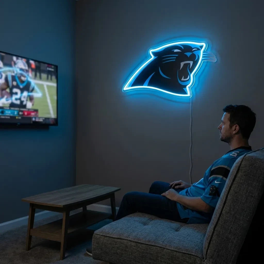 A man holding a large custom-shaped Carolina Panthers NFL football team logo LED neon sign featuring the fierce black panther head profile glowing in a vibrant process blue light