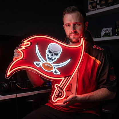 A man holding a large flag-shaped Tampa Bay Buccaneers NFL football team logo LED neon sign