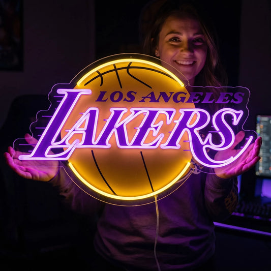 A woman holding a large glowing yellow and purple Los Angeles Lakers NBA basketball team LED neon sign