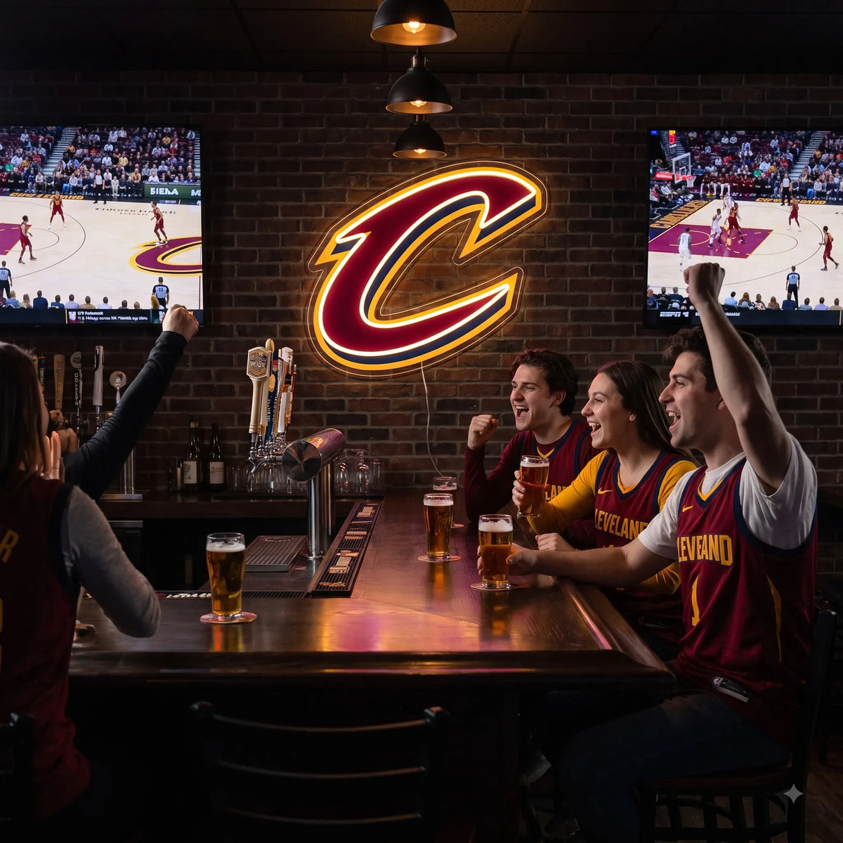 A man sitting at a gaming setup under a large glowing red and gold Cleveland Cavaliers NBA basketball team C logo LED neon sign mounted on a brick wall