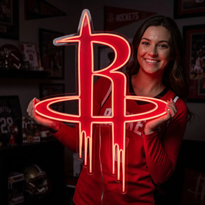 A smiling woman holding a large glowing red Houston Rockets NBA basketball team R logo LED neon sign